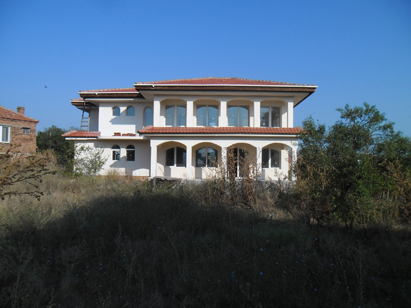 Back of house with overgrown weeds